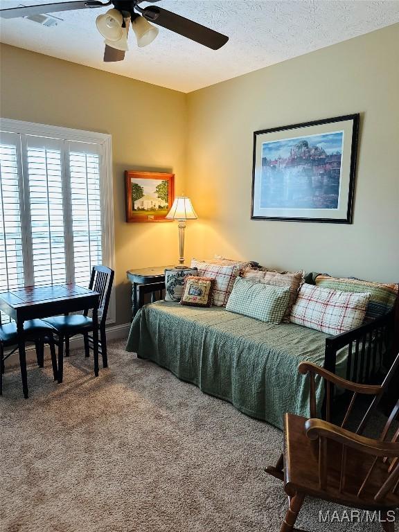 bedroom with a textured ceiling, ceiling fan, and carpet