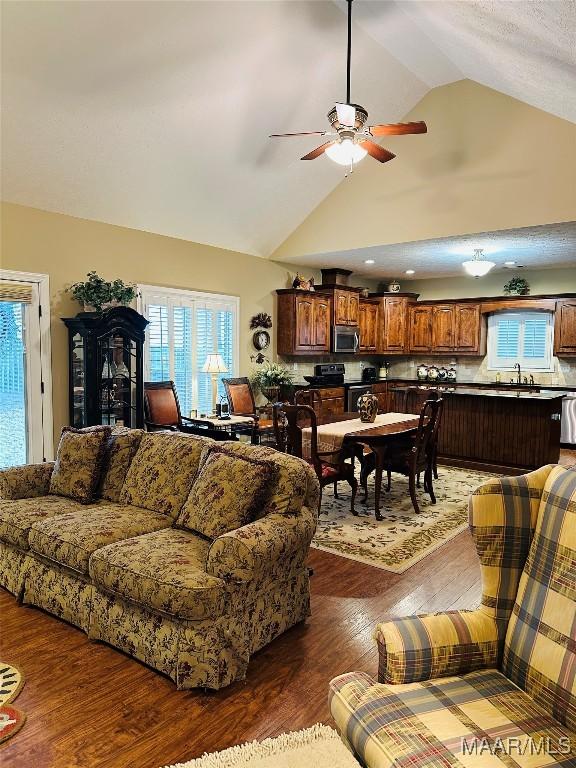 living room with vaulted ceiling, dark hardwood / wood-style floors, sink, and ceiling fan