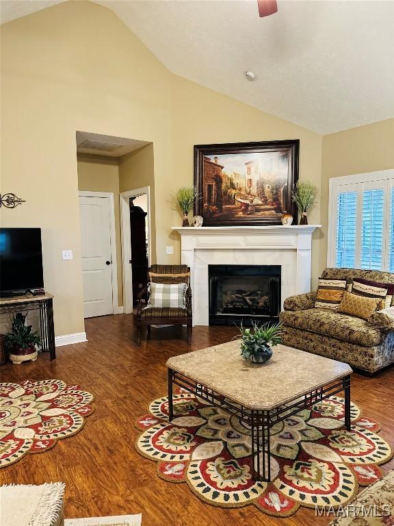 living room featuring ceiling fan, wood-type flooring, and vaulted ceiling