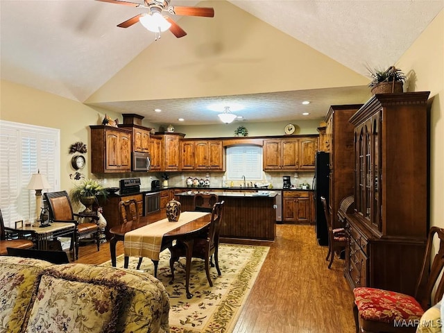 dining space with dark hardwood / wood-style flooring, sink, high vaulted ceiling, and ceiling fan