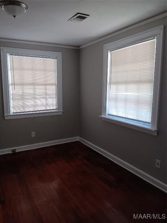 spare room featuring ornamental molding and dark hardwood / wood-style floors