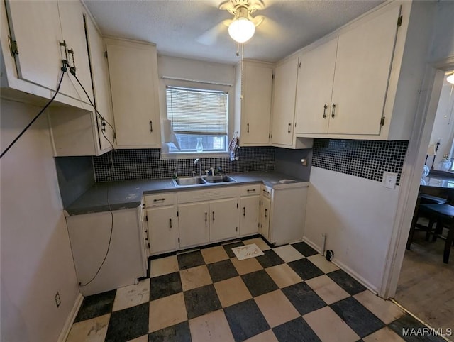 kitchen with tasteful backsplash, ceiling fan, sink, and white cabinets