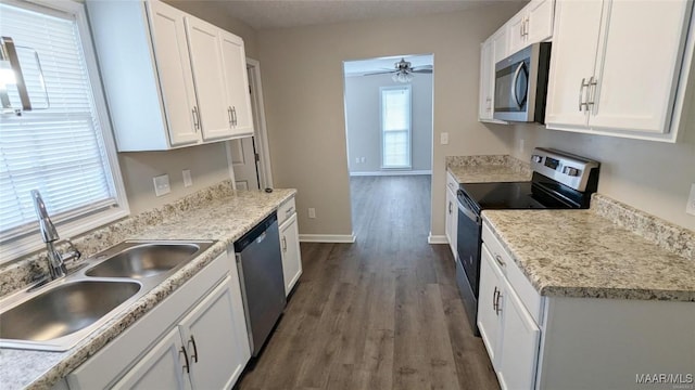 kitchen with sink, dark wood-type flooring, white cabinetry, stainless steel appliances, and a wealth of natural light