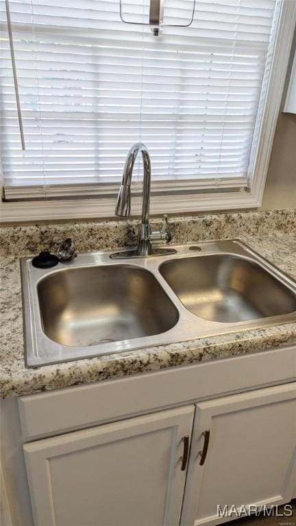 interior details featuring white cabinetry and sink