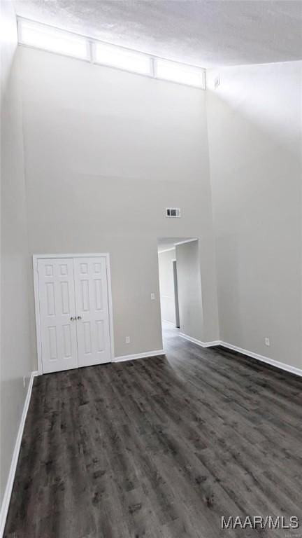 unfurnished room featuring dark wood-type flooring and a high ceiling