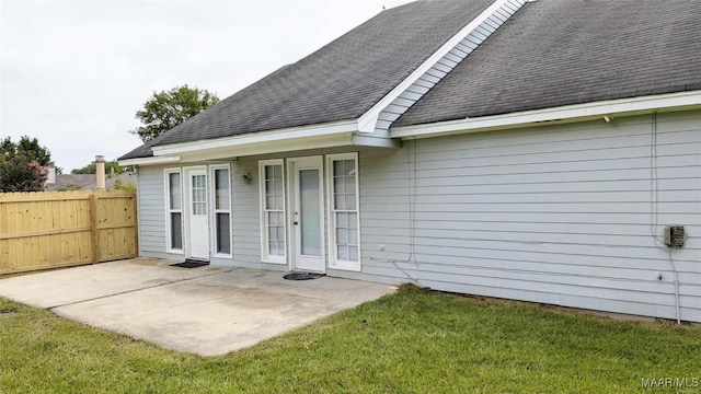 view of exterior entry with a lawn and a patio