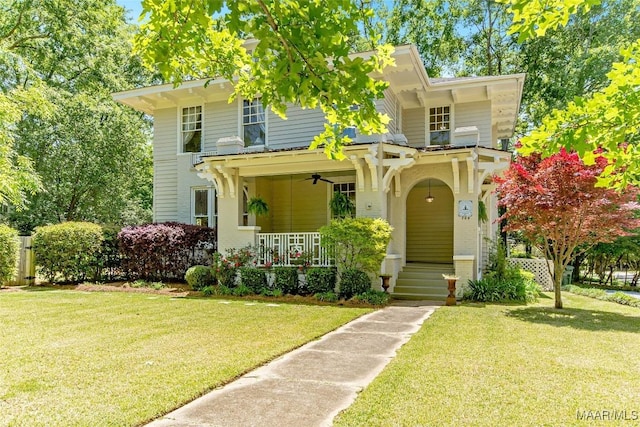 view of front facade with ceiling fan, covered porch, and a front lawn