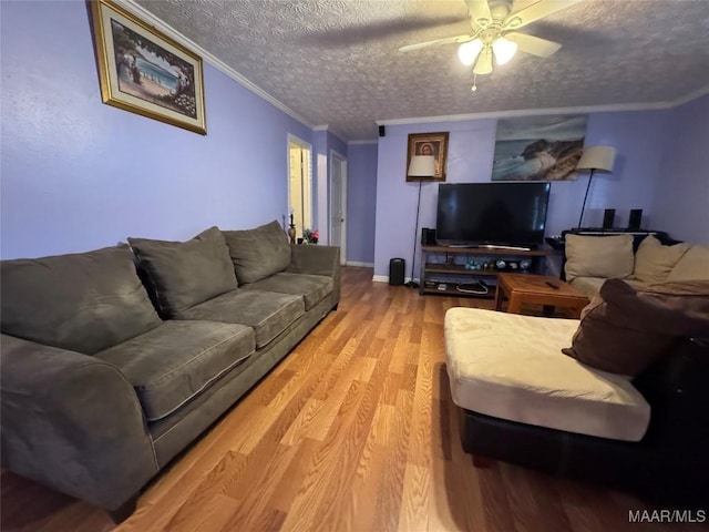 living room with ceiling fan, hardwood / wood-style flooring, ornamental molding, and a textured ceiling