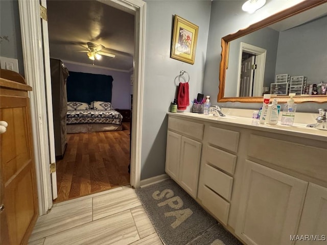 bathroom with wood-type flooring, ornamental molding, vanity, and ceiling fan