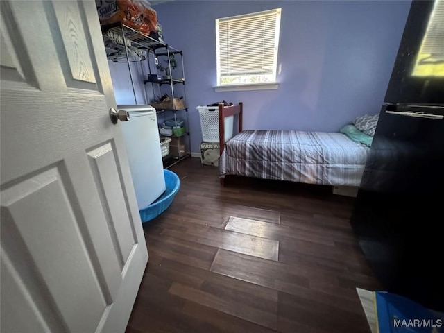 bedroom with black fridge and dark hardwood / wood-style floors