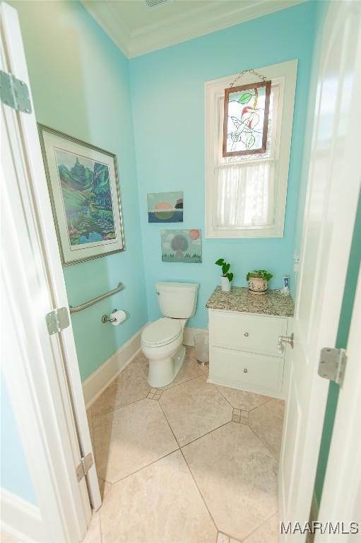 bathroom featuring crown molding, tile patterned floors, and toilet