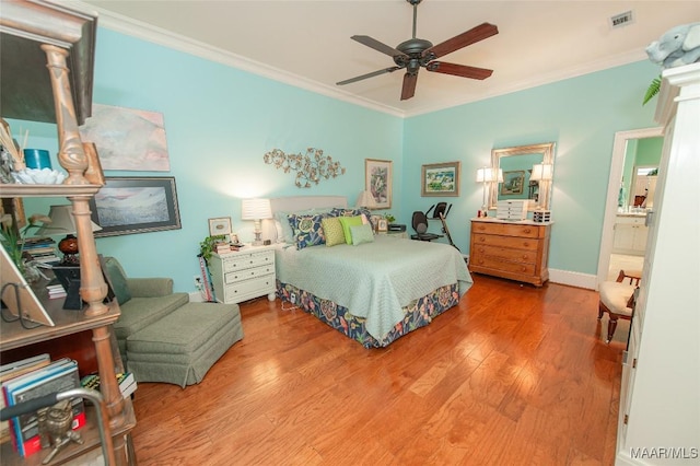 bedroom featuring crown molding, light wood-type flooring, ceiling fan, and ensuite bath