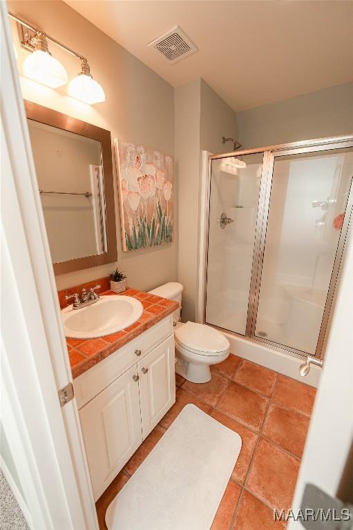 bathroom with walk in shower, vanity, toilet, and tile patterned flooring