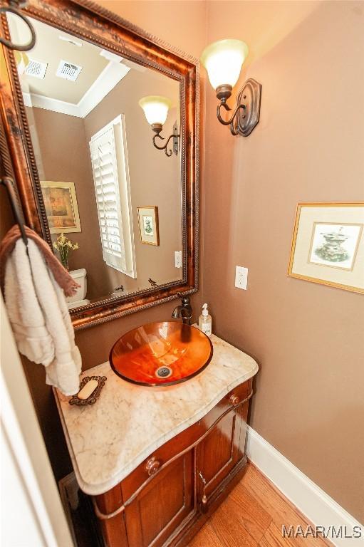 bathroom with vanity, hardwood / wood-style floors, and crown molding