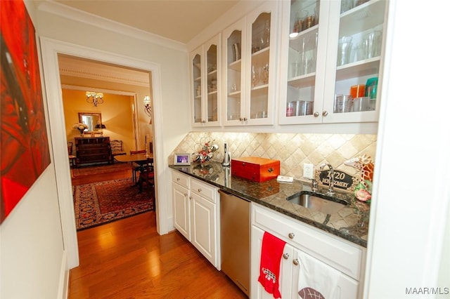 bar featuring white cabinetry, wood-type flooring, decorative backsplash, stainless steel dishwasher, and dark stone counters