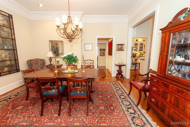 dining space with ornamental molding, wood-type flooring, and an inviting chandelier