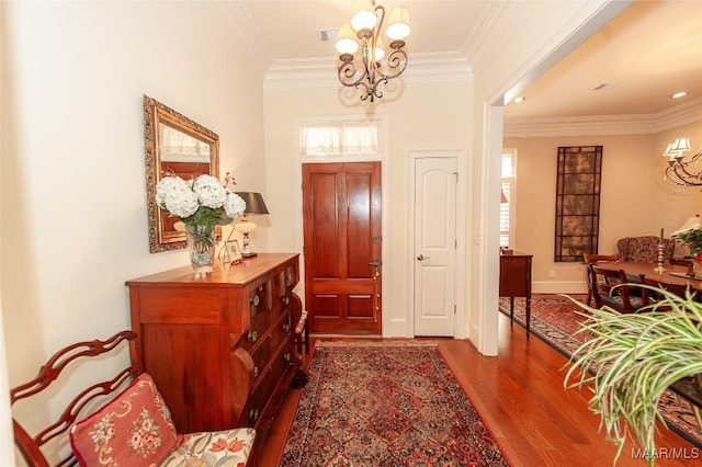 entryway featuring dark wood-type flooring, crown molding, and a notable chandelier