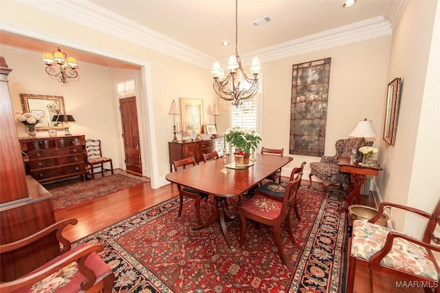 dining room featuring an inviting chandelier, ornamental molding, and hardwood / wood-style flooring