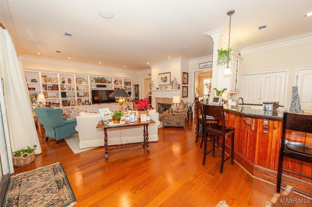 living room featuring hardwood / wood-style floors, crown molding, and sink