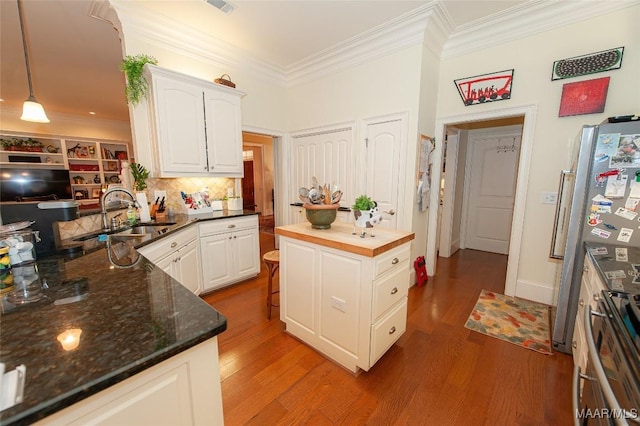 kitchen with sink, dark stone countertops, white cabinets, decorative light fixtures, and kitchen peninsula