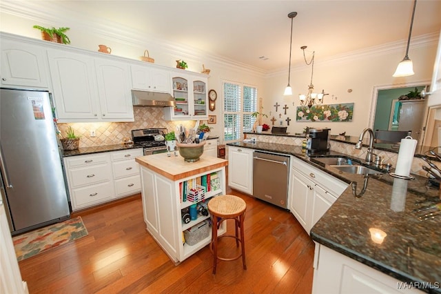 kitchen featuring sink, stainless steel appliances, white cabinets, a kitchen island, and decorative light fixtures