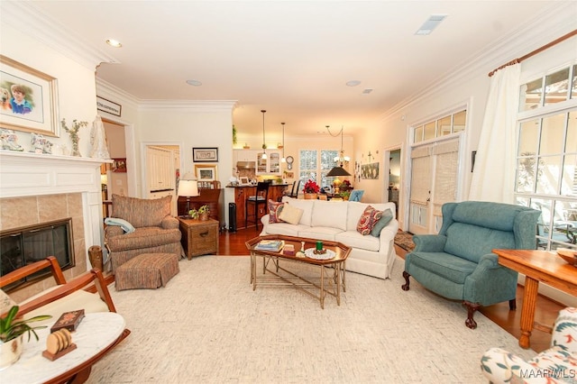 living room featuring crown molding, a tile fireplace, and hardwood / wood-style flooring