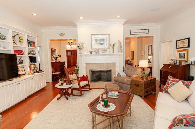 living room featuring hardwood / wood-style flooring, ornamental molding, and a tiled fireplace