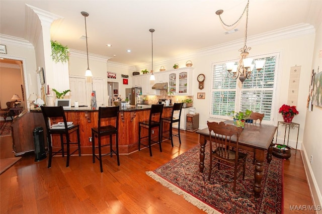 dining area featuring a notable chandelier, crown molding, and hardwood / wood-style flooring