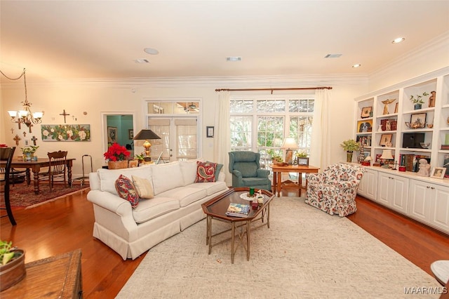 living room with hardwood / wood-style flooring, crown molding, and a notable chandelier