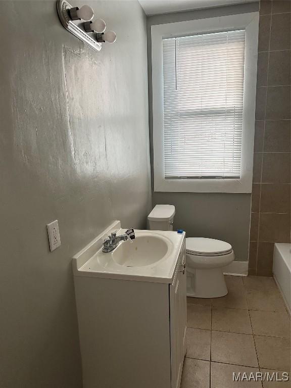 bathroom featuring tile patterned floors, toilet, a bath, and plenty of natural light