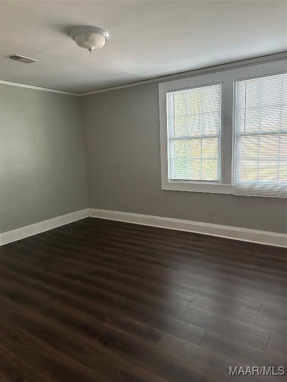 spare room featuring crown molding and dark wood-type flooring