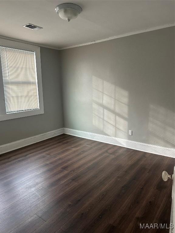 spare room featuring crown molding and dark wood-type flooring