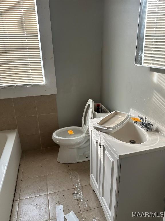 bathroom with tile patterned flooring, vanity, a tub, and toilet