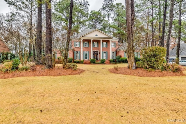 neoclassical home featuring brick siding and a front lawn