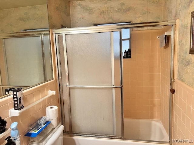 bathroom with bath / shower combo with glass door, toilet, tile walls, and decorative backsplash