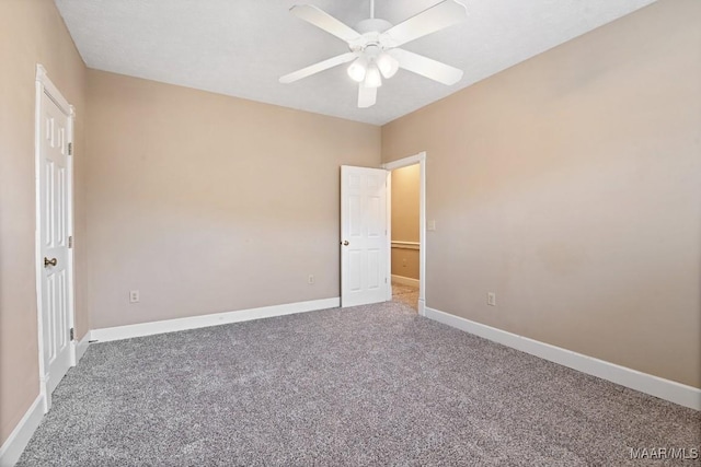 empty room with carpet floors, a ceiling fan, and baseboards