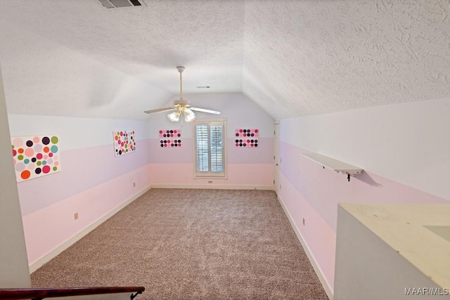 additional living space featuring a textured ceiling, ceiling fan, carpet floors, baseboards, and vaulted ceiling