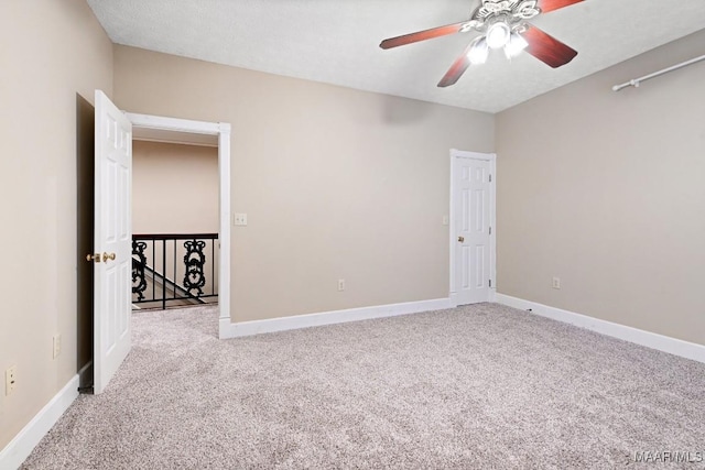 spare room featuring light colored carpet, ceiling fan, and baseboards