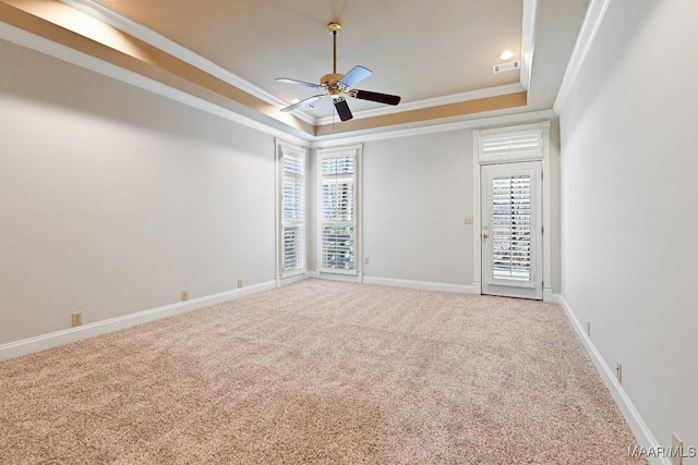 carpeted empty room with baseboards, visible vents, a raised ceiling, a ceiling fan, and ornamental molding