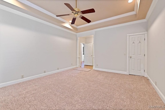 empty room featuring ornamental molding, a tray ceiling, ceiling fan, and light colored carpet