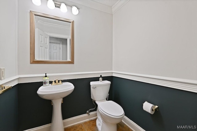 half bath featuring baseboards, tile patterned flooring, ornamental molding, and toilet