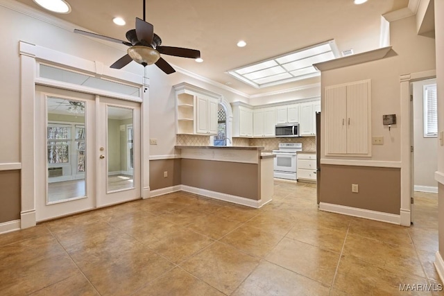 kitchen with a peninsula, stainless steel microwave, a ceiling fan, crown molding, and electric stove