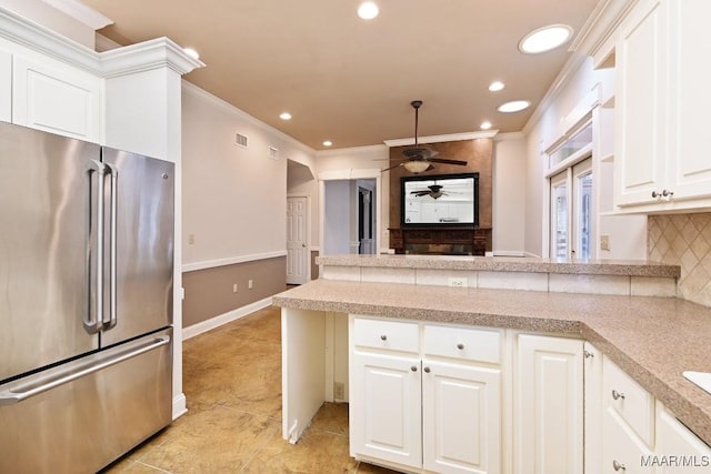 kitchen with a ceiling fan, light tile patterned floors, backsplash, a peninsula, and freestanding refrigerator