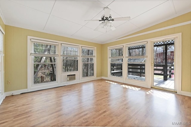 empty room featuring vaulted ceiling, wood finished floors, a ceiling fan, an AC wall unit, and baseboards