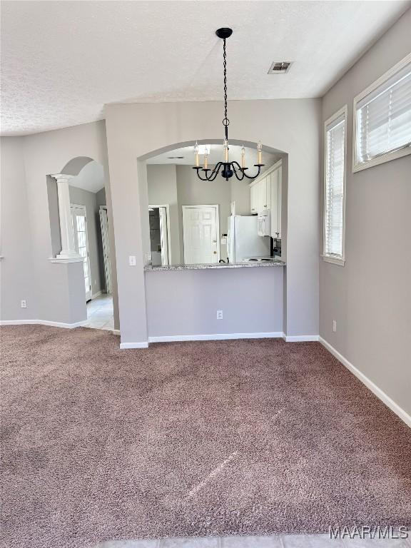 interior space featuring carpet, a healthy amount of sunlight, a chandelier, and a textured ceiling