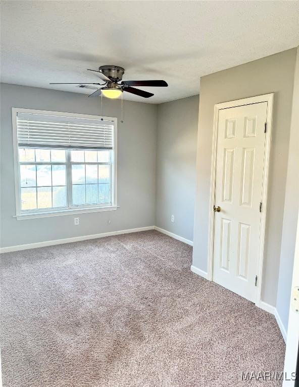 empty room featuring ceiling fan and carpet floors