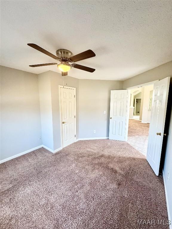 carpeted empty room with ceiling fan and a textured ceiling