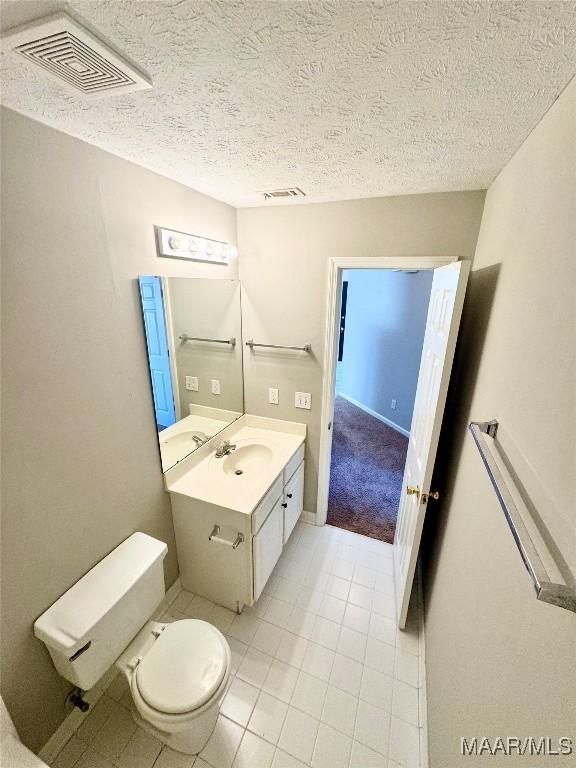 bathroom featuring vanity, a textured ceiling, tile patterned floors, and toilet