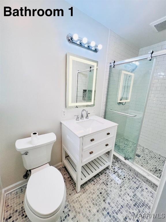 bathroom with tile patterned flooring, vanity, a shower with shower door, and toilet