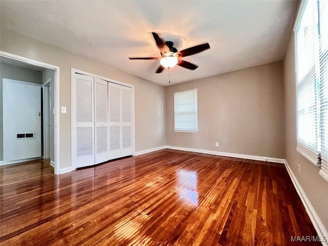 unfurnished bedroom featuring hardwood / wood-style flooring, ceiling fan, and a closet